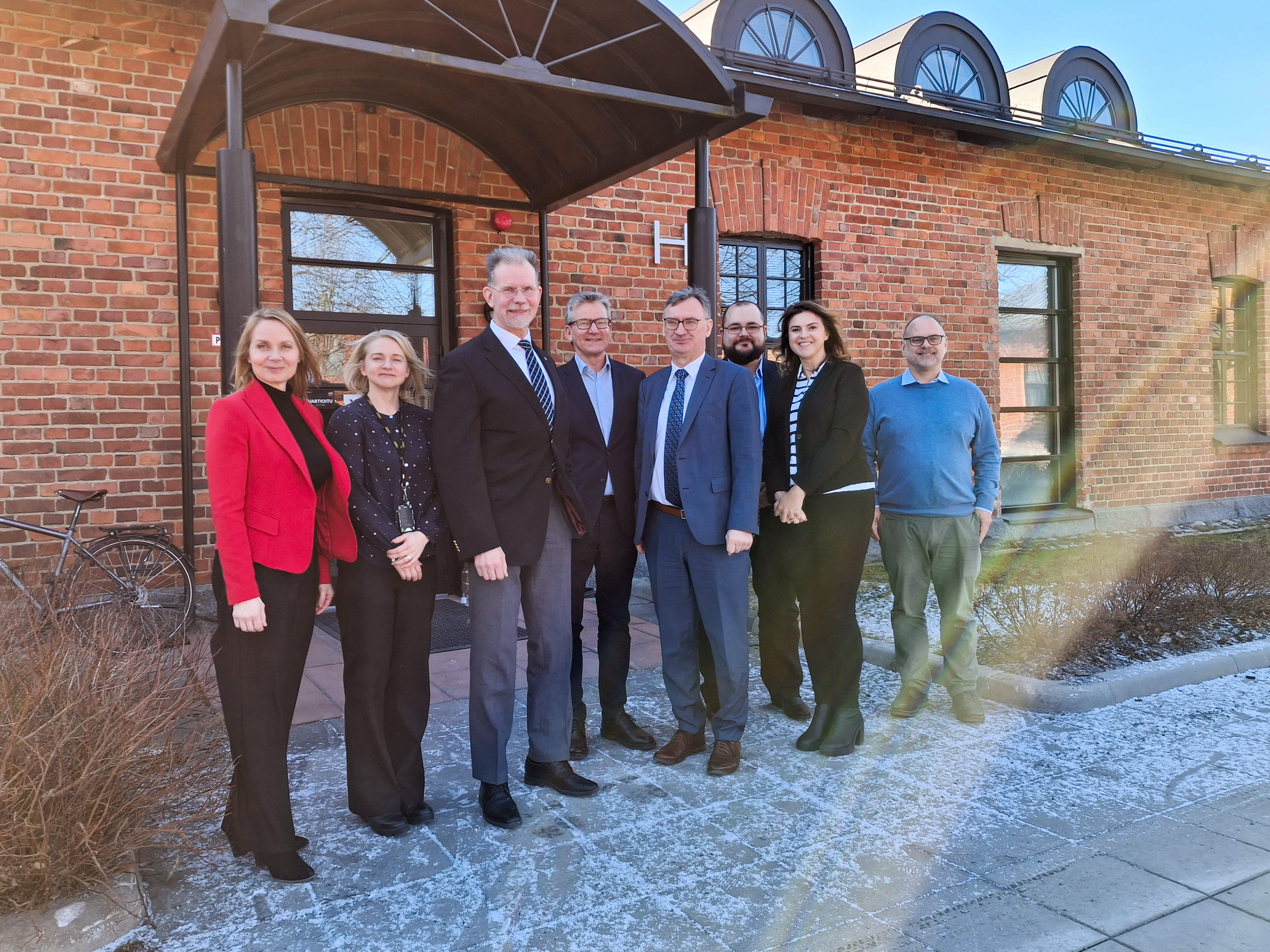 HKA visitors and Xamk staff pictured outside in front of a red brick building in Mikkeli