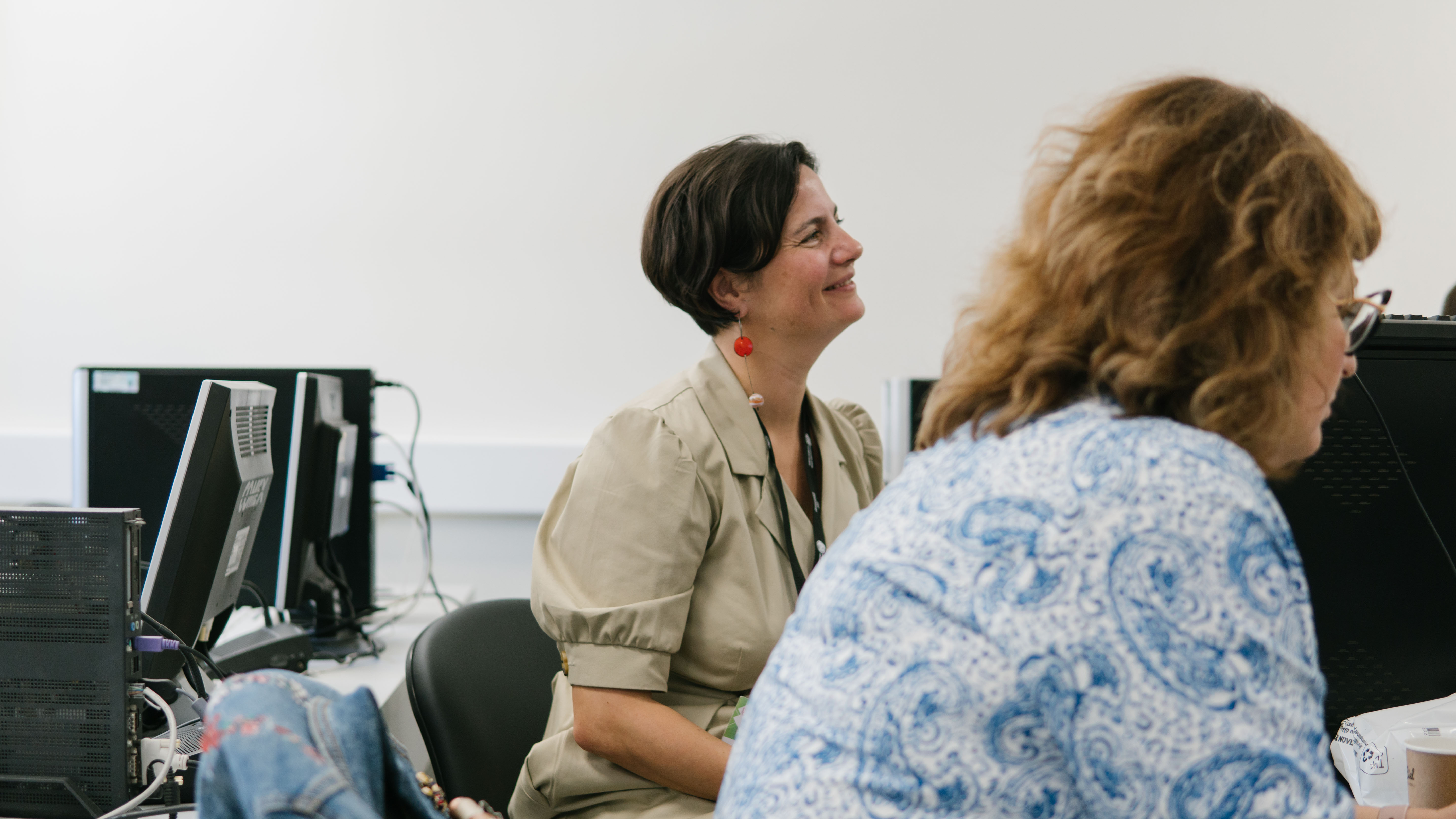 Elisaveta is sitting down and watching to the right.