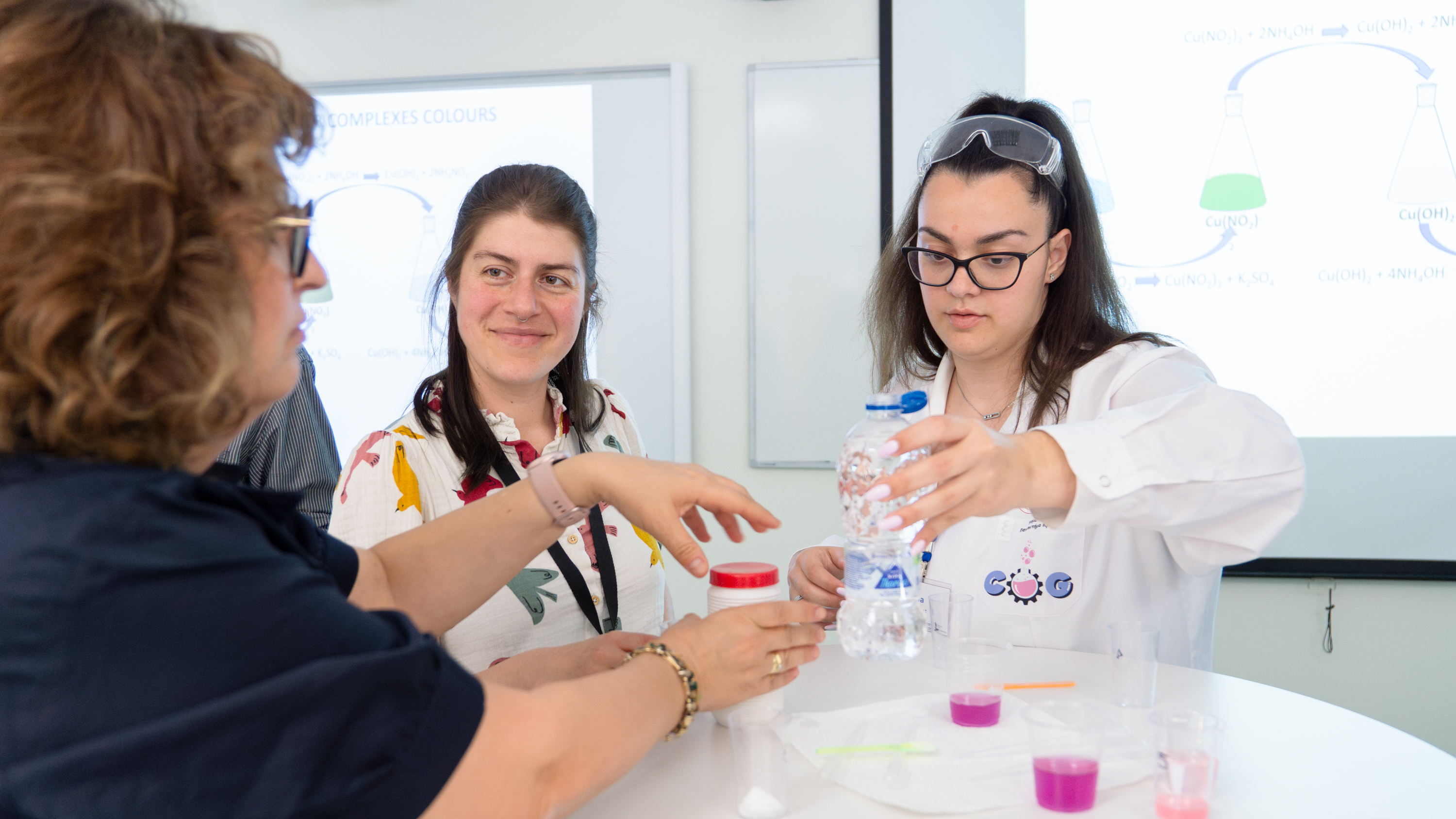 Three persons around a table mixing fluids.