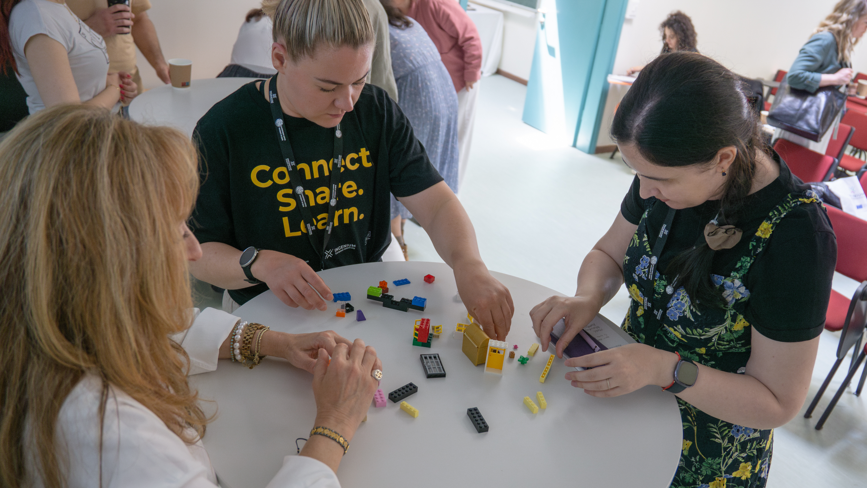 Three persons around a table building Legos.