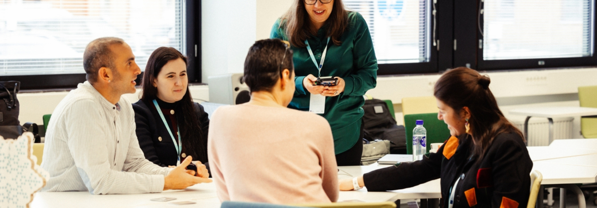 Five persons discussing around a table
